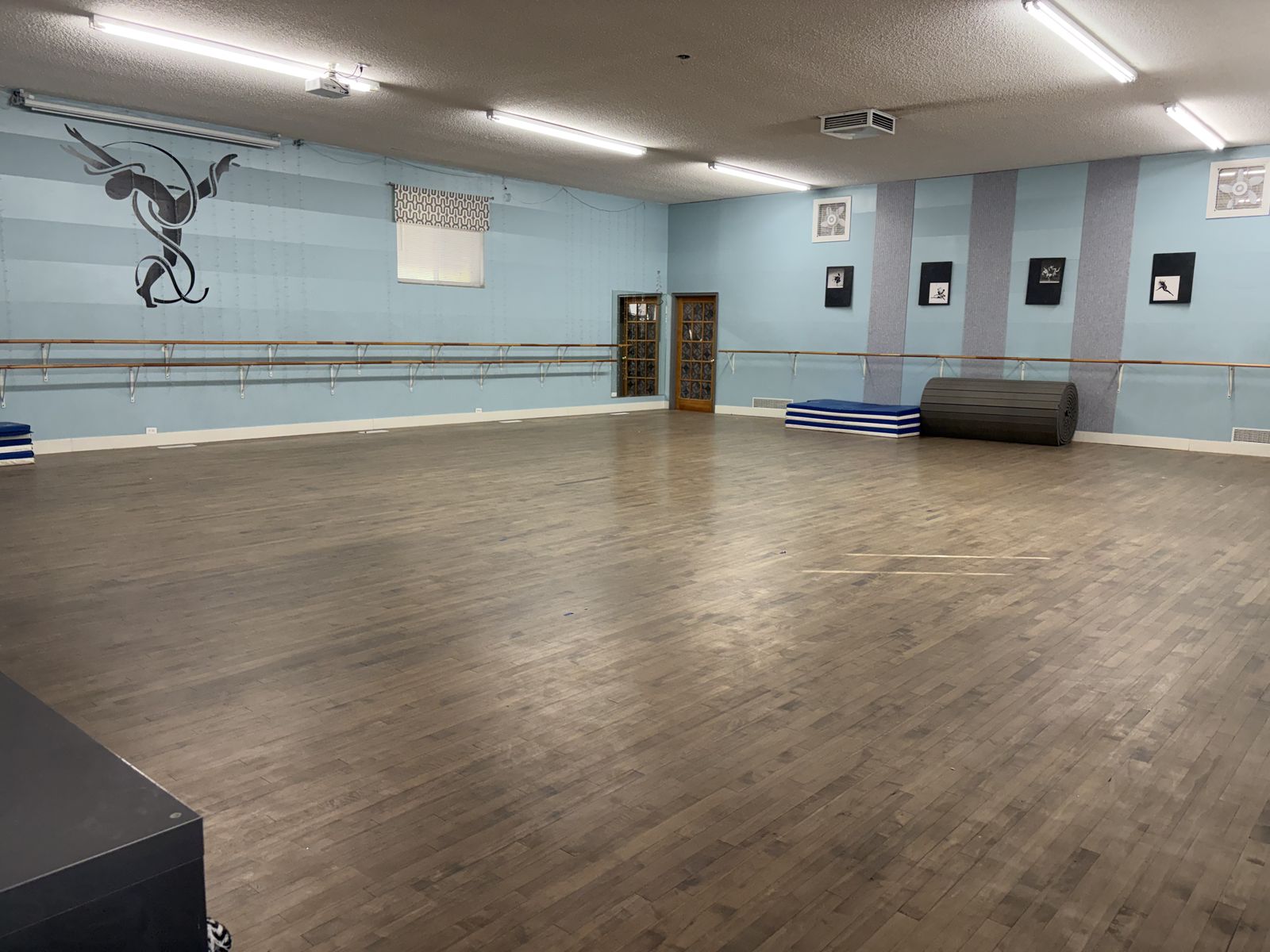The pilot class space at Syracuse Dance Academy: a large wood-floor studio lined with ballet barres